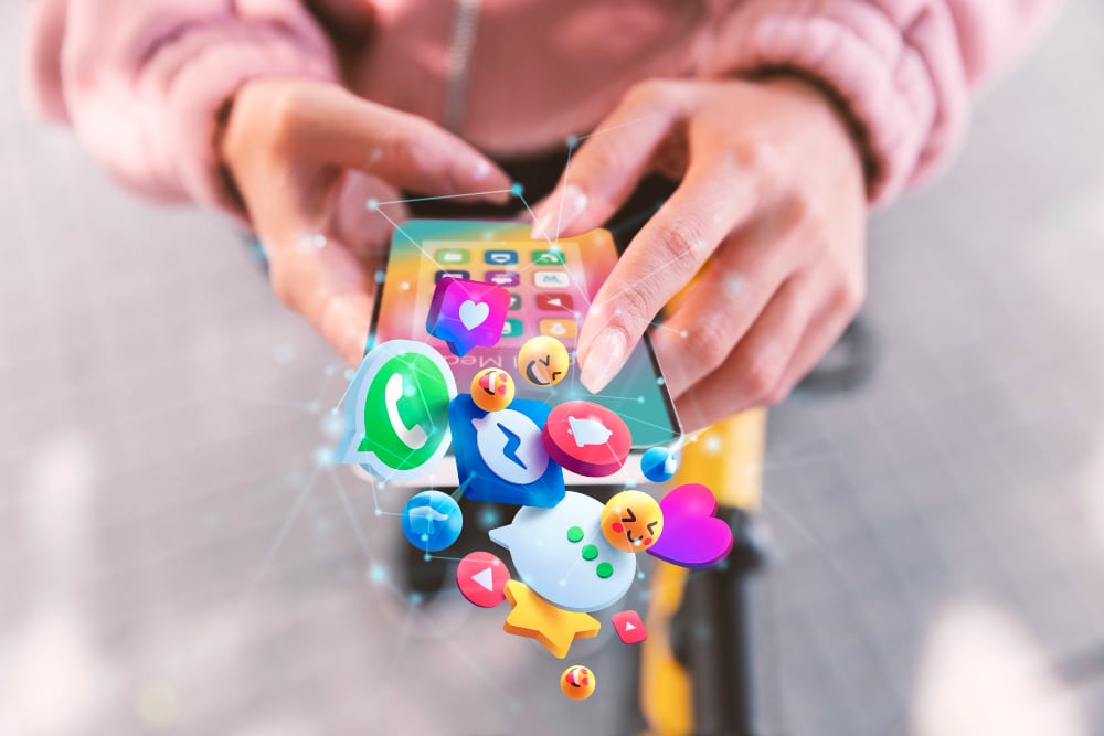 A small business owner uses a smartphone, with various colorful app icons like social media, messaging, and games appearing to float above the device, hinting at effective small business marketing strategies.