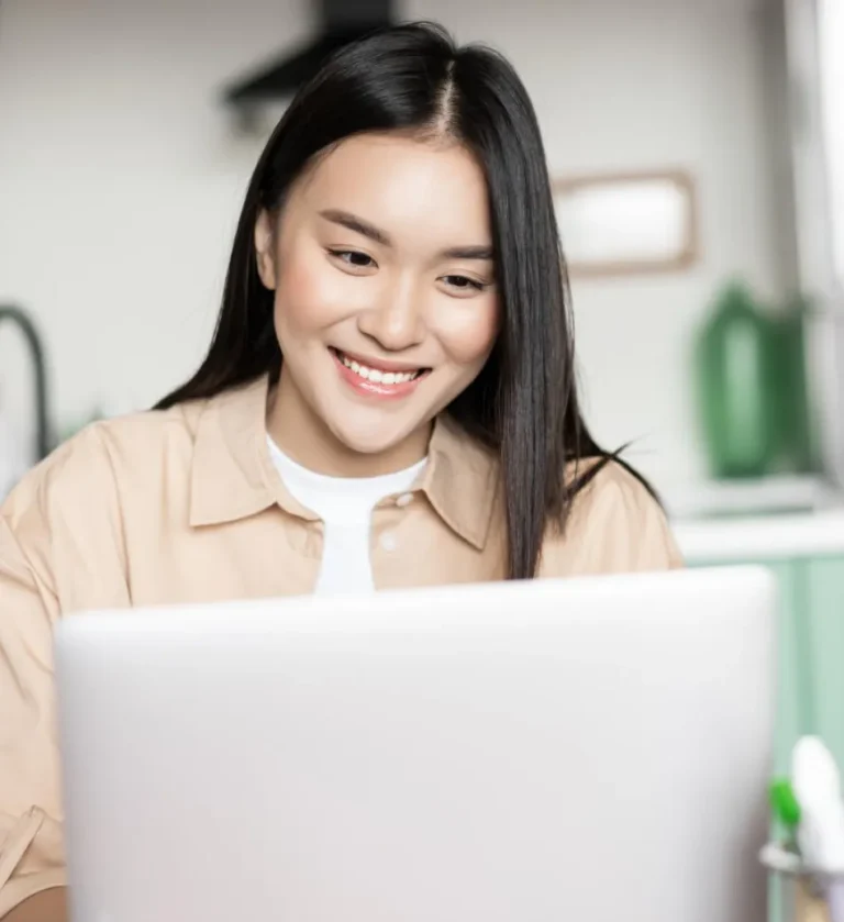 A smiling asian woman using a laptop for Website Protection.